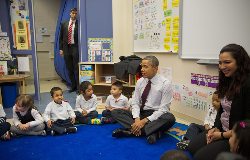 President Barack Obama sits on the floor with young students