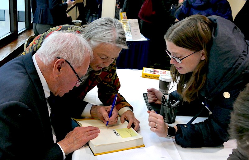 Photo of Gilbert Grosvenor signing books.